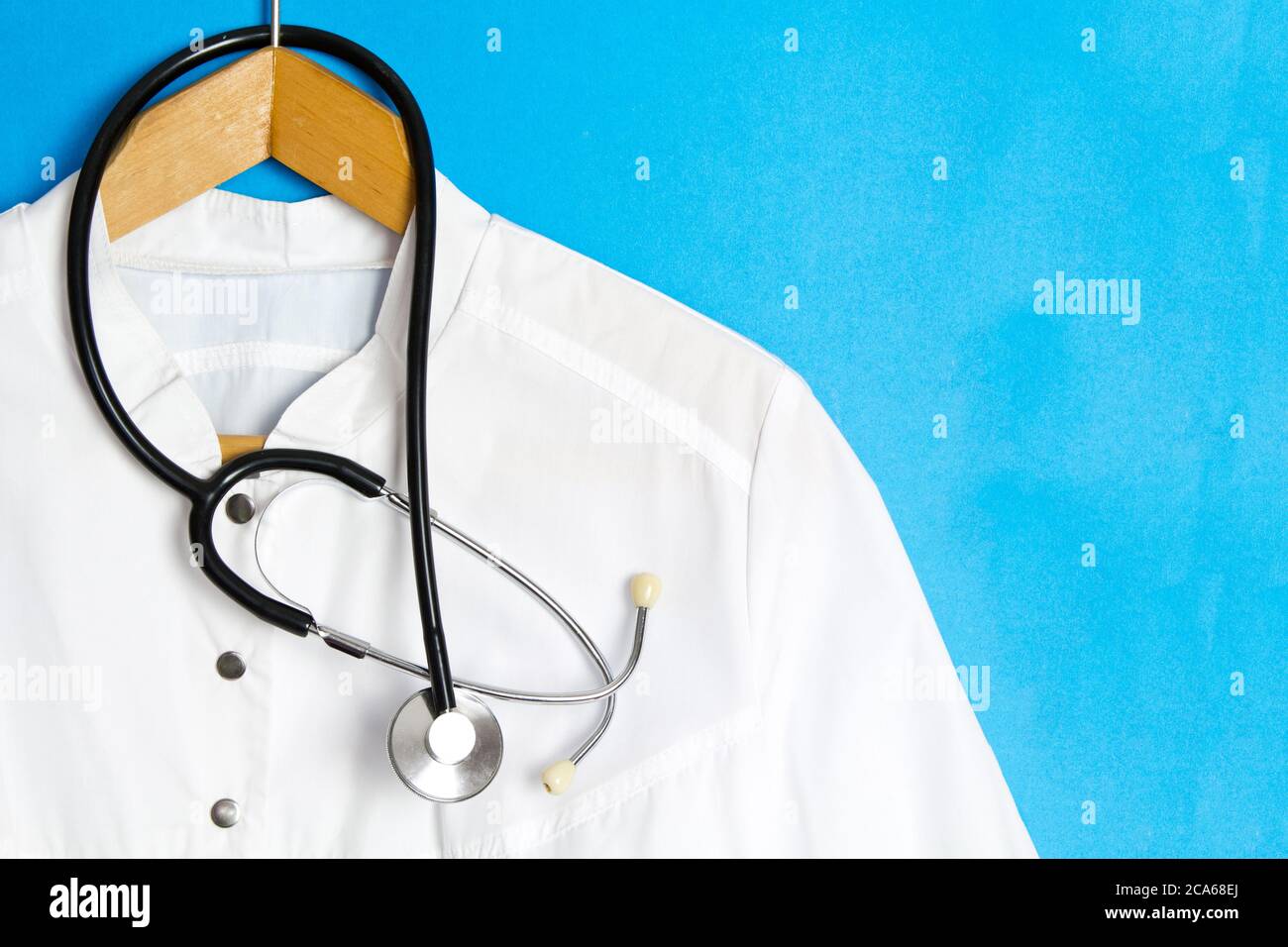 Le Doctor's est équipé d'un stéthoscope sur un cintre. Blouse du médecin sur fond bleu. Espace publicitaire, espace de copie, modèle médical Banque D'Images