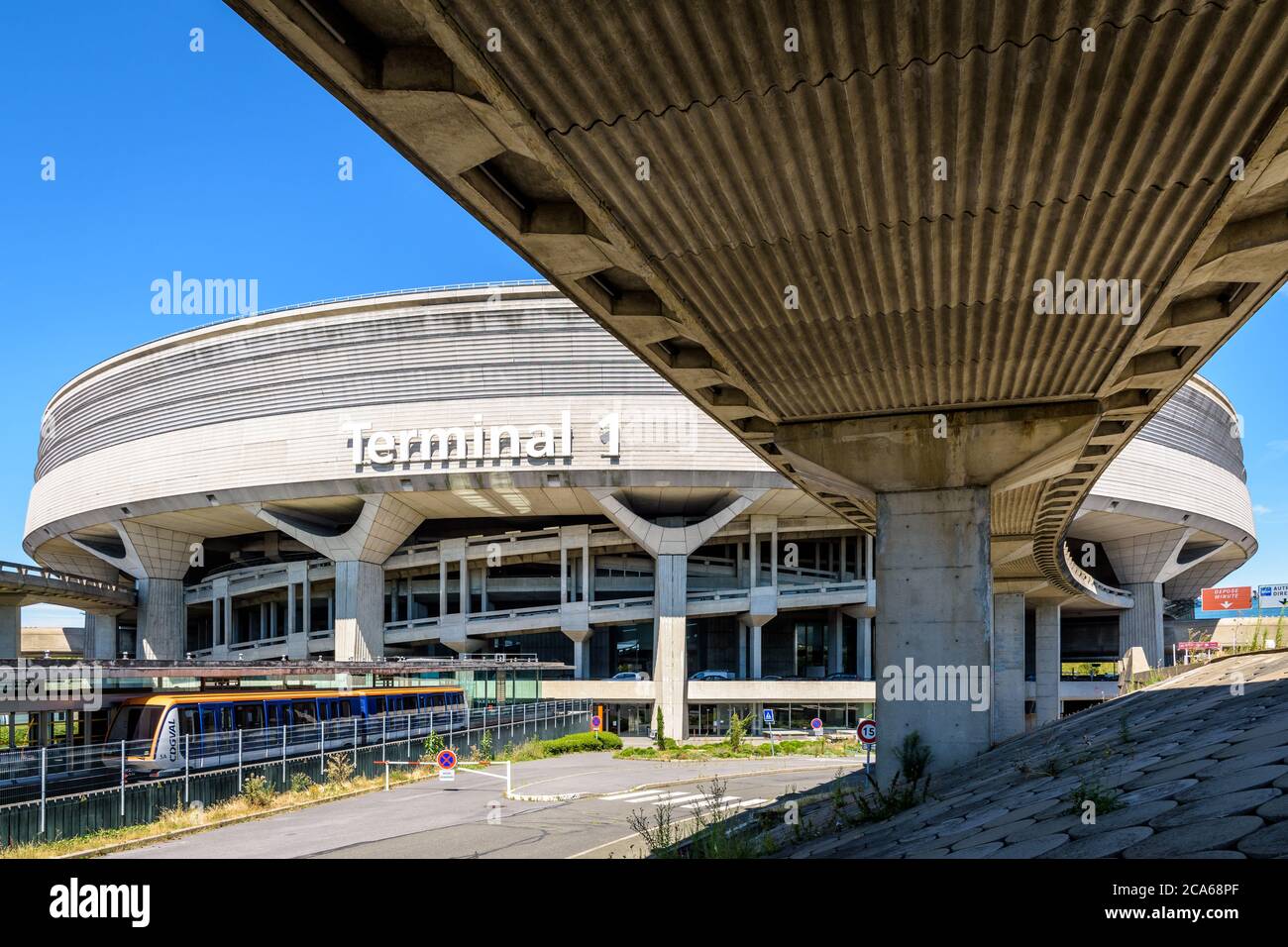 Le bâtiment circulaire du terminal 1 de l'aéroport Paris-Charles de Gaulle est desservi par divers moyens d'accès comme les routes, les rampes et la navette de l'aéroport CDGVAL. Banque D'Images