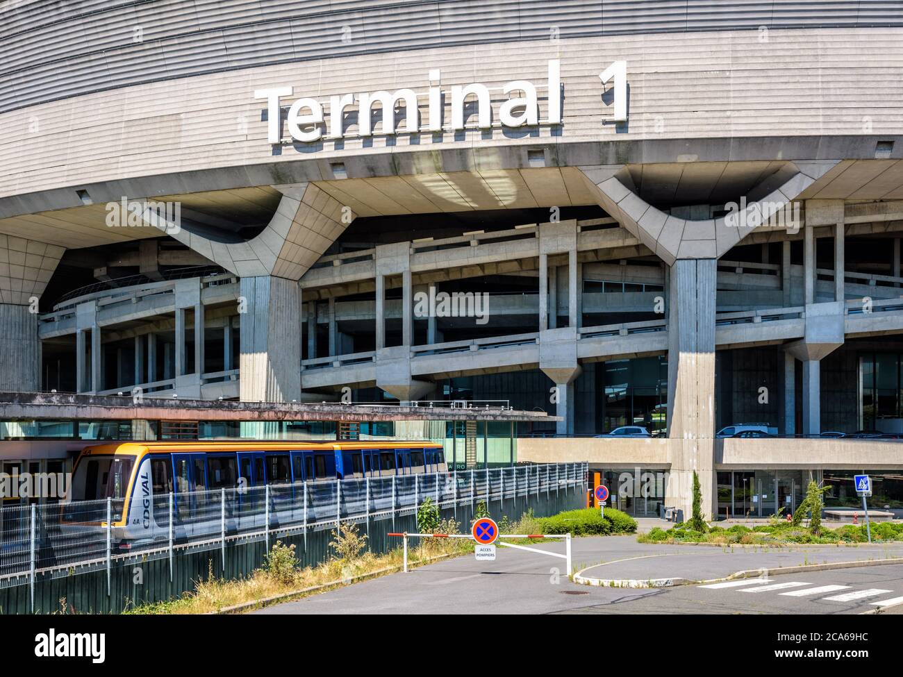 Une navette aéroport CDGVAL est en service à la gare au pied du bâtiment circulaire en béton du terminal 1 de l'aéroport Paris-Charles de Gaulle. Banque D'Images