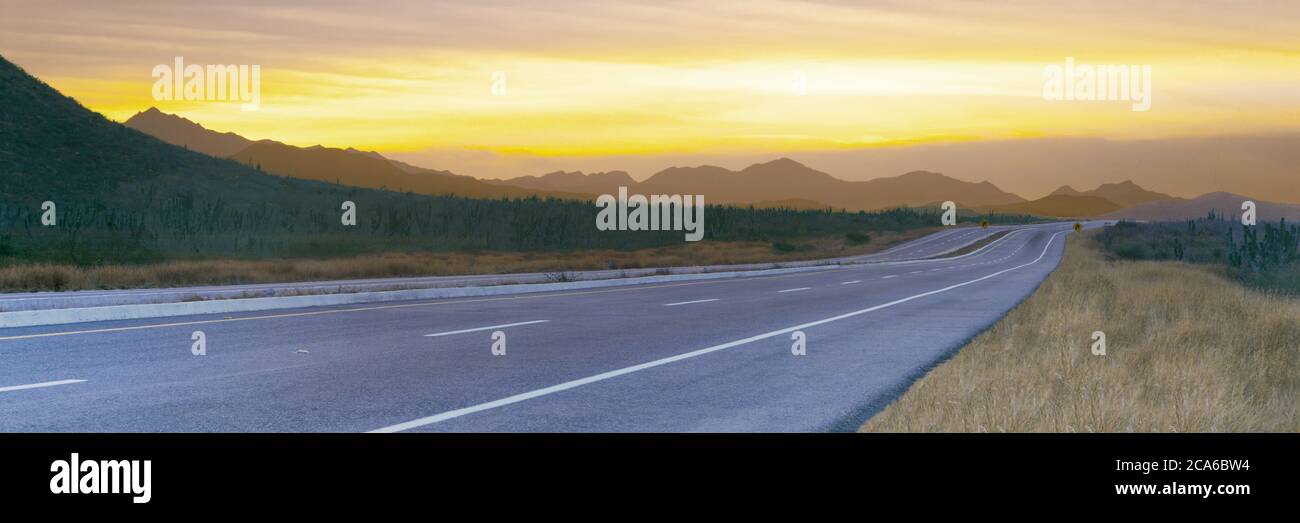 Lever de soleil au-dessus de l'autoroute 19 et de la chaîne de montagnes de la Sierra de la Laguna, Todos Santos, Baja California sur, Mexique Banque D'Images