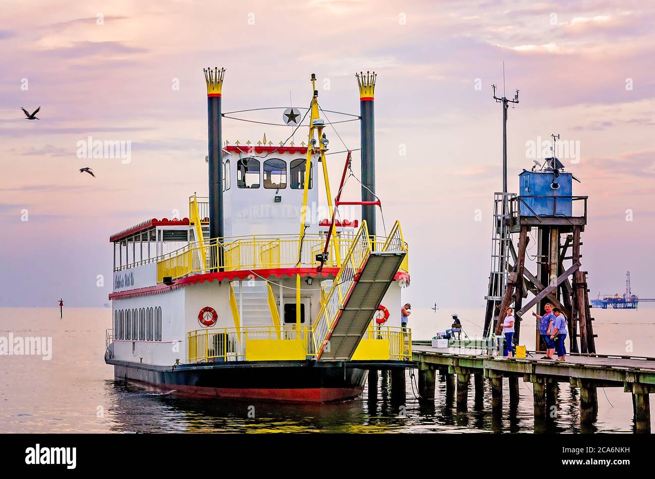 Les gens pêchent sur la jetée publique à côté du bateau de fête à aubes Spirit of Texas, le 1er août 2014, à Dauphin Island, Alabama. Banque D'Images