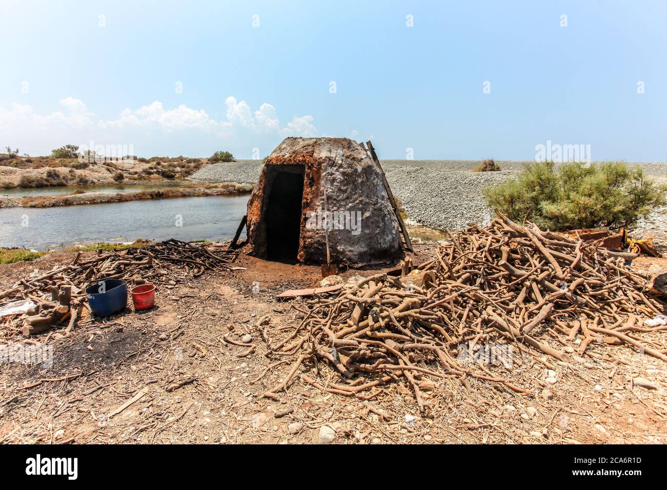 Petit four en pierre sur la plage, utilisé pour brûler les racines d'arbre pour le charbon de bois Banque D'Images