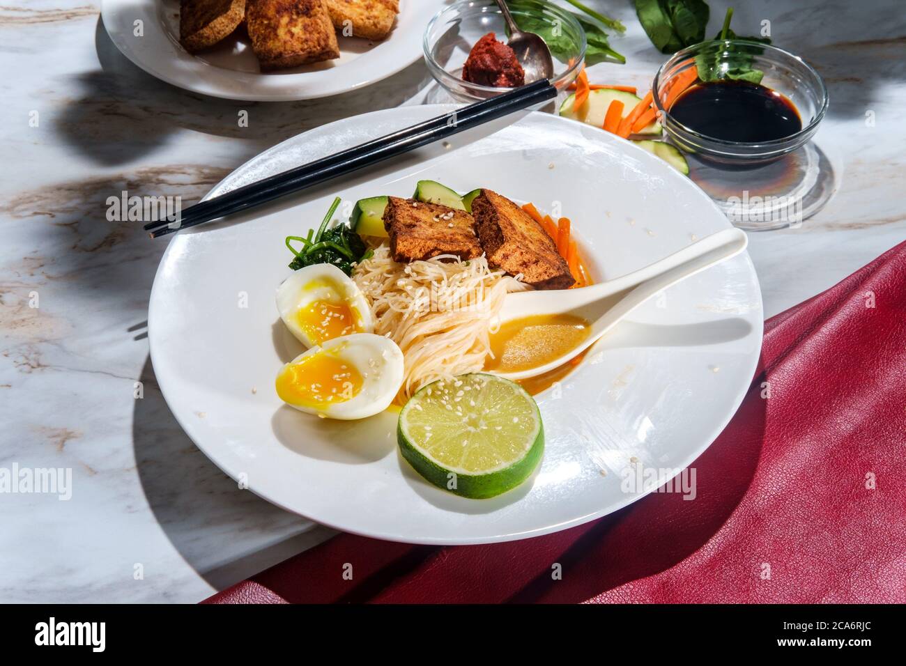 Soupe thaïlandaise de nouilles de riz au curry rouge accompagnée de tofu frits croustillants et d'œufs durs Banque D'Images