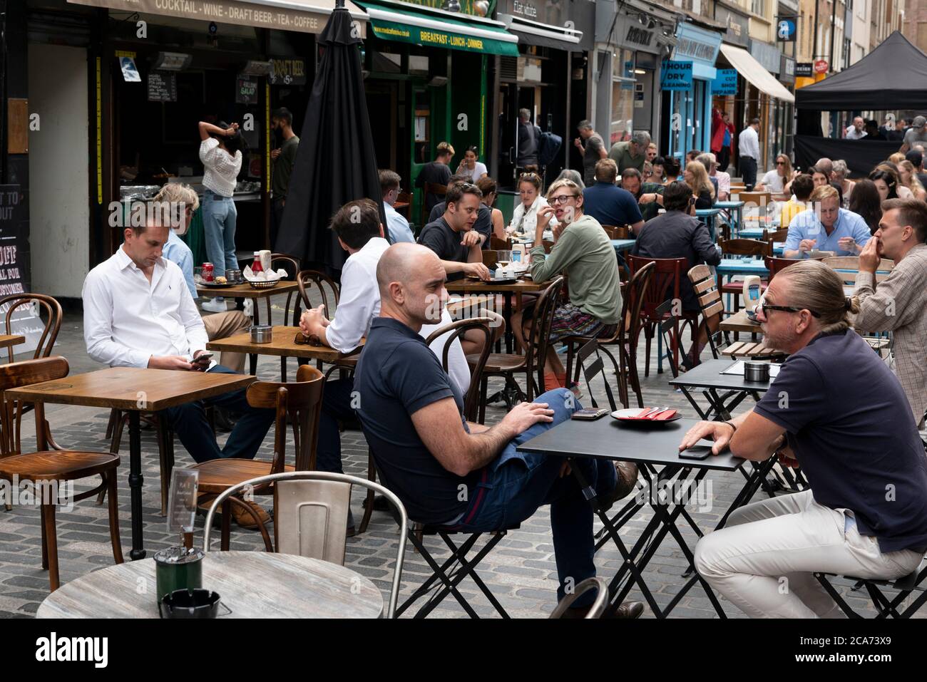 Les clients peuvent manger aux tables de restaurant en plein air de Soho pendant le programme manger à l'extérieur pour aider les clients à profiter d'une réduction sur les repas pour aider à stimuler les restaurants et les pubs après le confinement. Banque D'Images