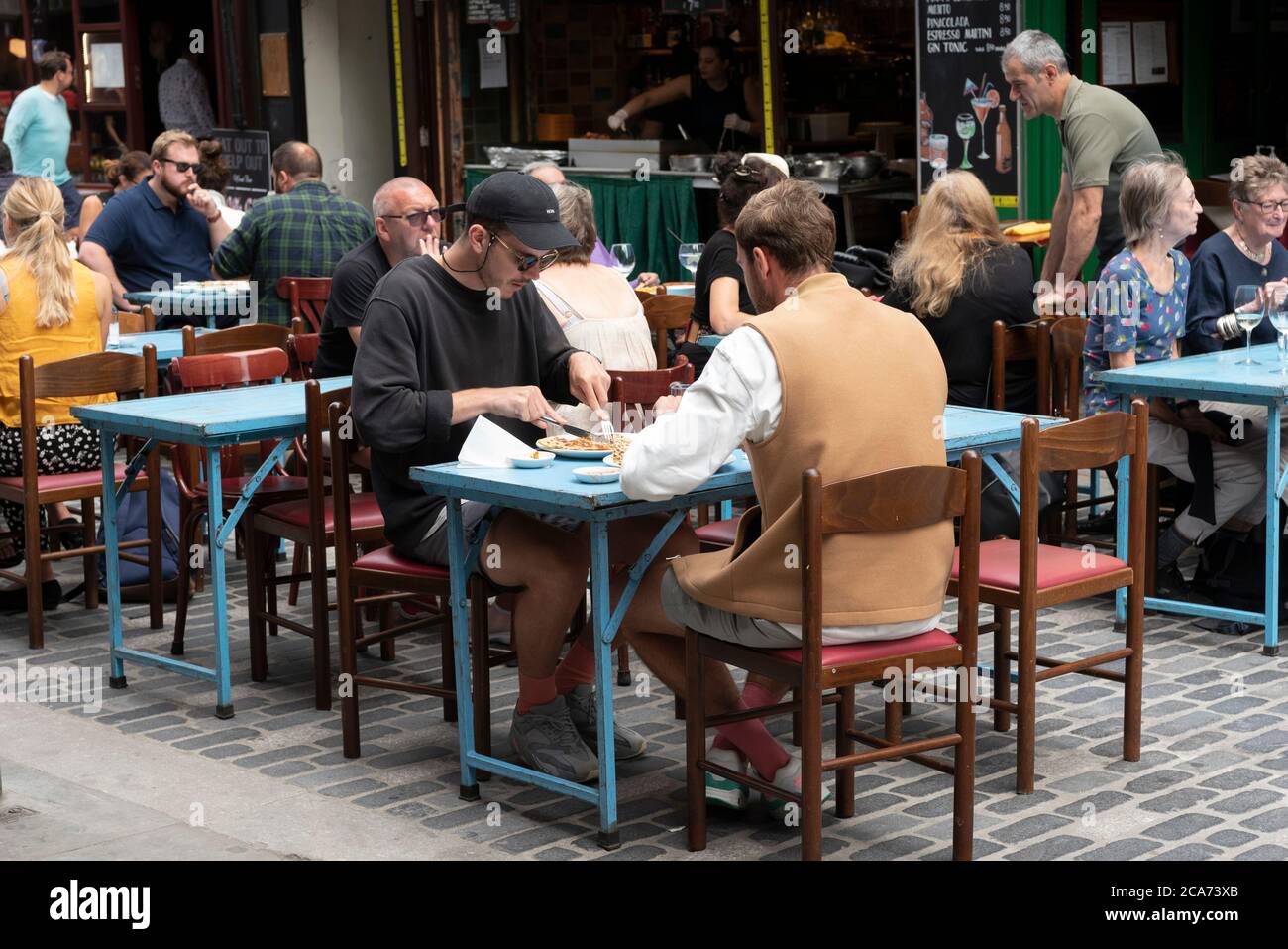 Les clients peuvent manger aux tables de restaurant en plein air de Soho pendant le programme manger à l'extérieur pour aider les clients à profiter d'une réduction sur les repas pour aider à stimuler les restaurants et les pubs après le confinement. Banque D'Images