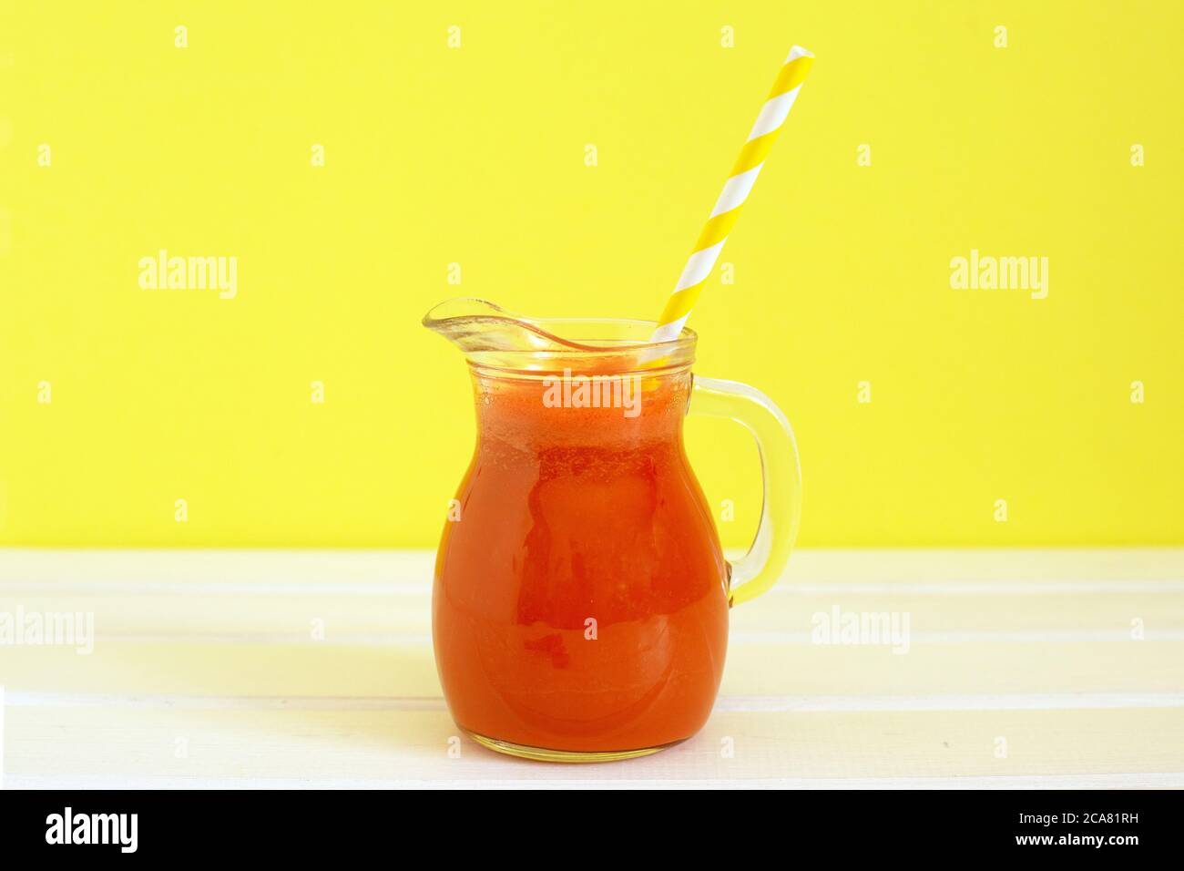 Carafe de jus de carotte avec tube à cocktail sur fond de couleur. Alimentation saine de Detox, régime alcalin. Concept alimentaire d'été. Banque D'Images