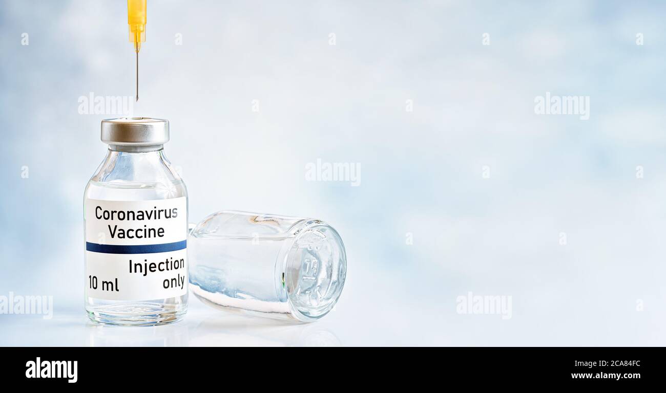 Concept de vaccin contre le coronavirus, flacon en verre avec capuchon argenté sur le bureau blanc, aiguille hypodermique de seringue orange à injecter, IR d'espace de fond flou Banque D'Images