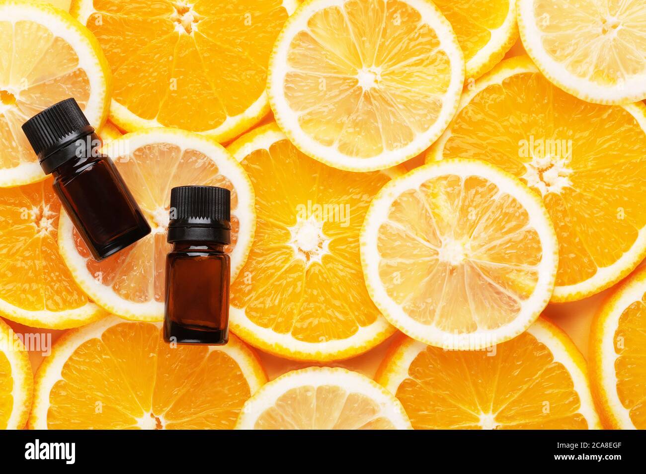 Vue de dessus de l'huile essentielle biologique. Produits cosmétiques naturels. Récipients en verre avec liquide. Des tranches d'orange et de citron sur l'arrière-plan, placez-les pour le texte. Banque D'Images