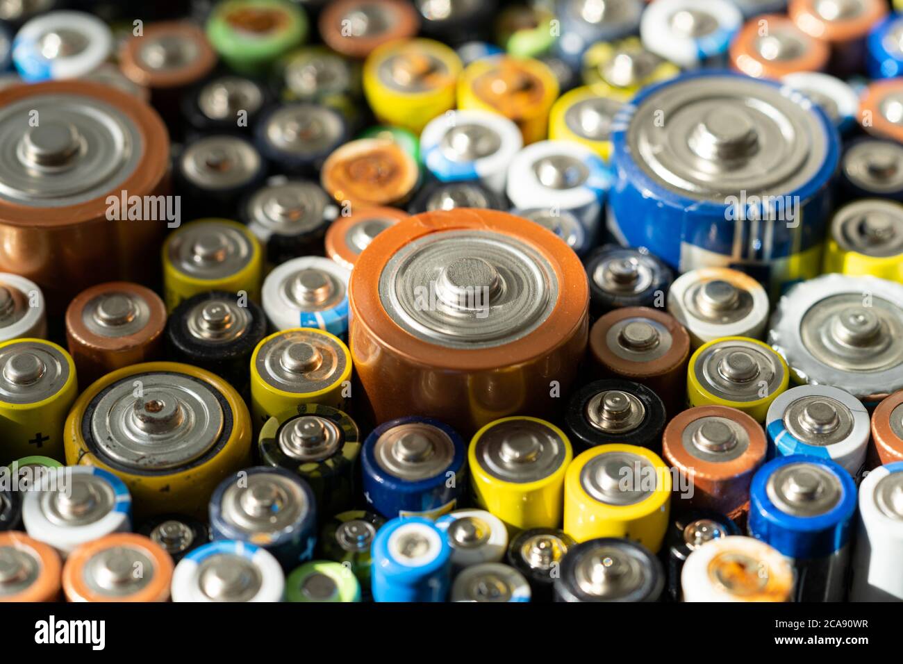 Gros plan des extrémités positives des batteries déchargées de différentes tailles et formats, mise au point sélective. Batterie usagée pour recyclage. Produit pour déchets dangereux Banque D'Images