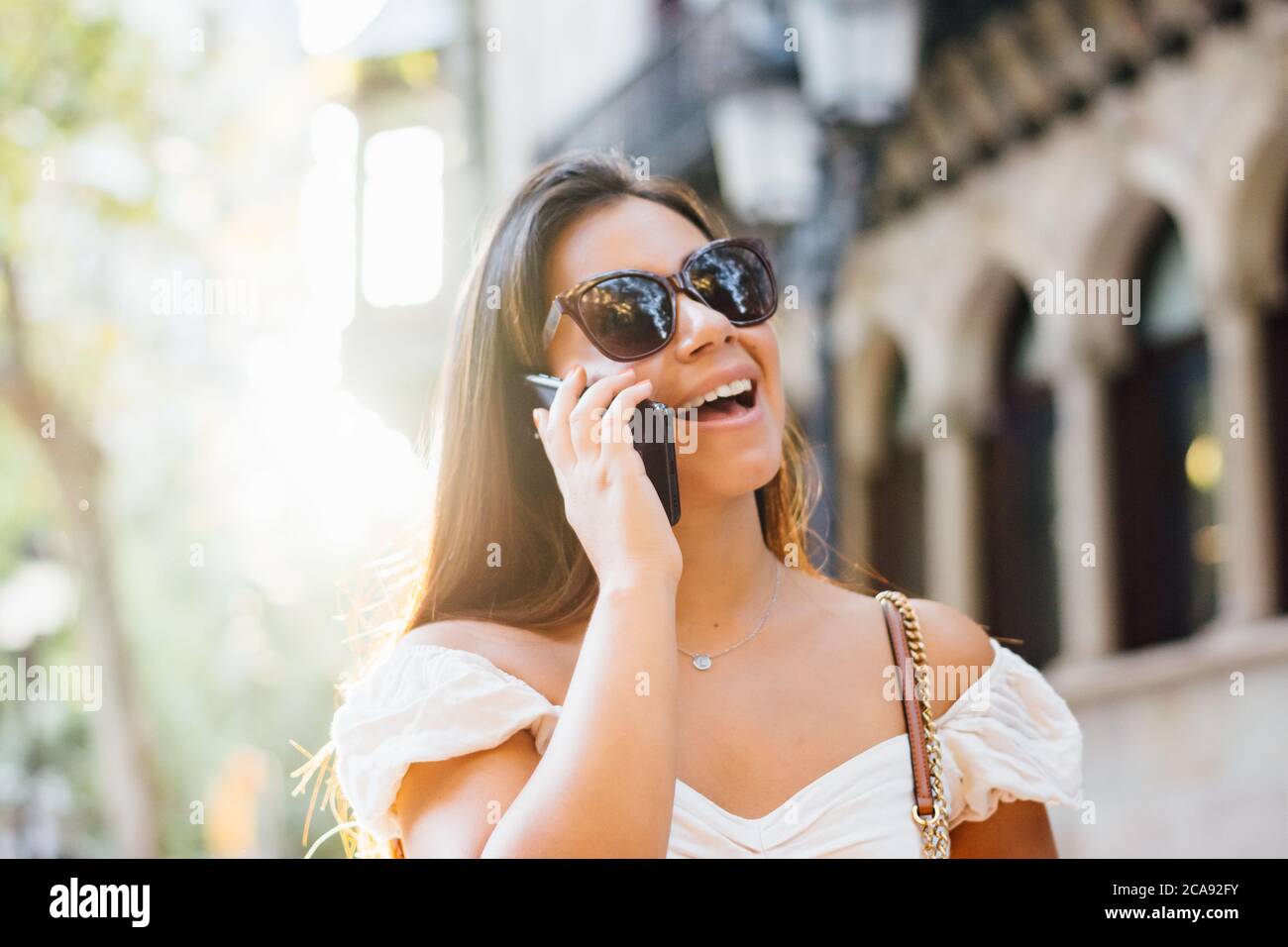 une femme avec des lunettes de soleil parle au téléphone autour de la ville Banque D'Images