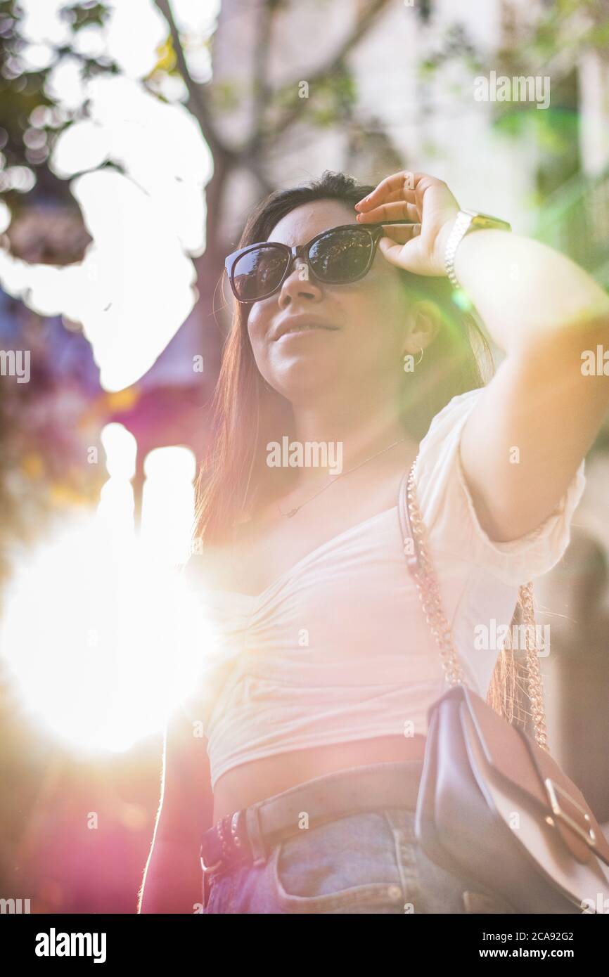 une femme avec des lunettes de soleil sourit lorsqu'elle se promène dans la ville Banque D'Images