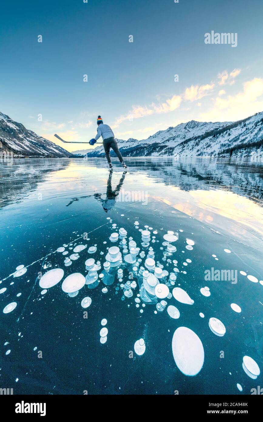 Joueur de hockey sur glace patinant sur le lac gelé Sils couvert de bulles, Engadine, canton de Graubunden, Suisse, Europe Banque D'Images