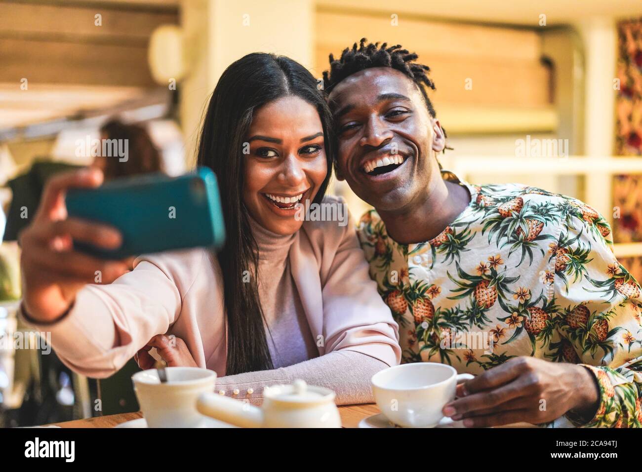 Heureux couple noir de boire du café dans la boulangerie tout en prenant selfie avec le téléphone mobile - jeunes s'amuser avec les tendances de la technologie - médias sociaux Banque D'Images