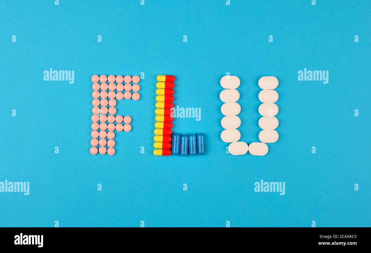 Saison de la grippe ou concept de la grippe. Le mot grippe fait à partir de l'assortiment de pilules et de capsules sur fond bleu. Thème de la pharmacie, soins de santé, médicaments prescrits Banque D'Images