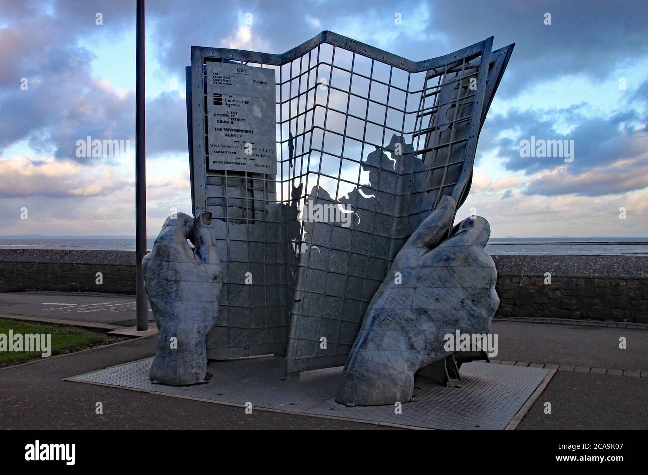 Une œuvre d'art à deux mains tenant un journal en quadrillage sur le front de mer de Minehead Banque D'Images