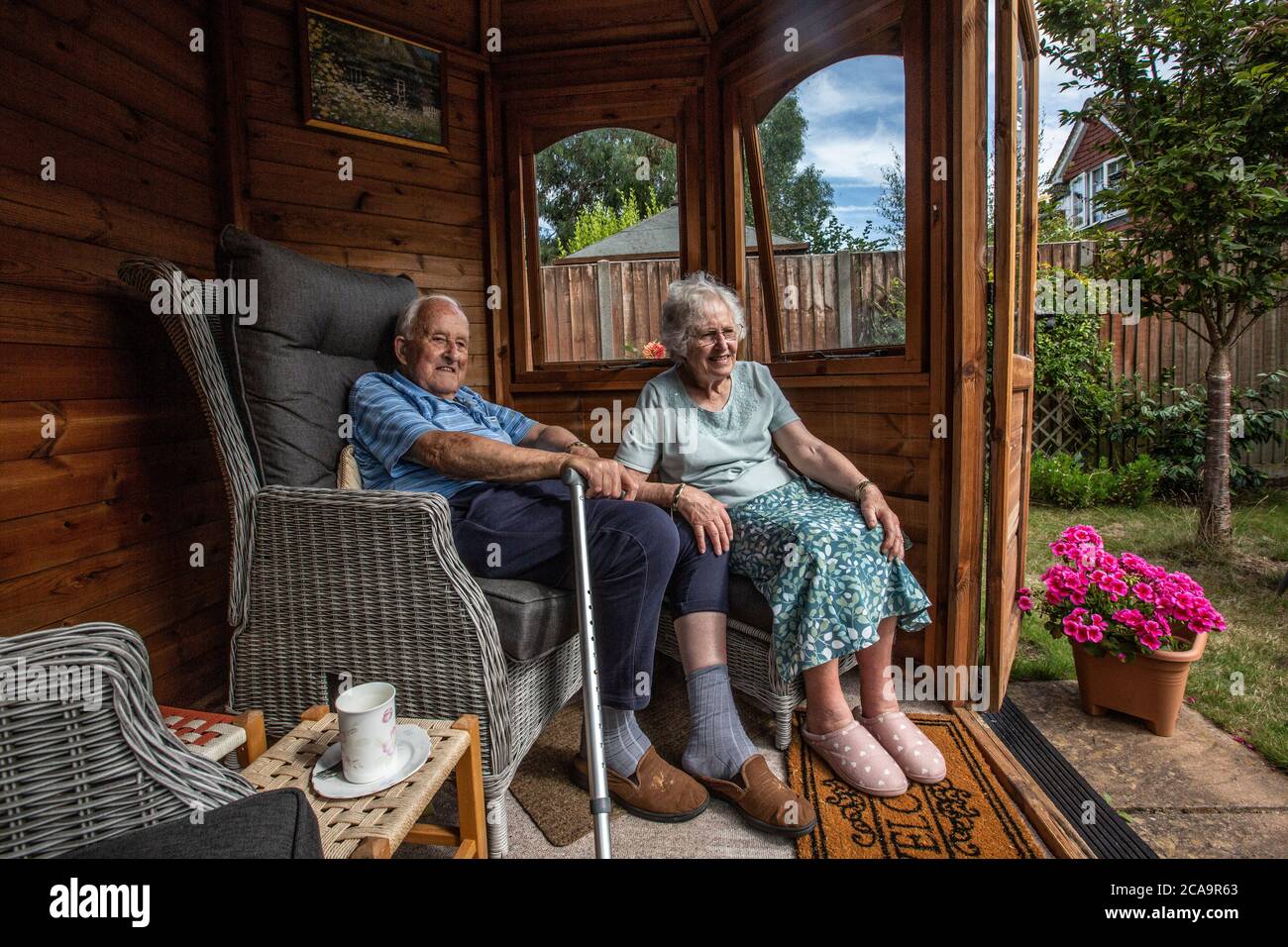 Couple de personnes âgées dans leurs années 80 appréciant le temps chaud d'été dans leur jardin d'été maison, Angleterre, Royaume-Uni Banque D'Images