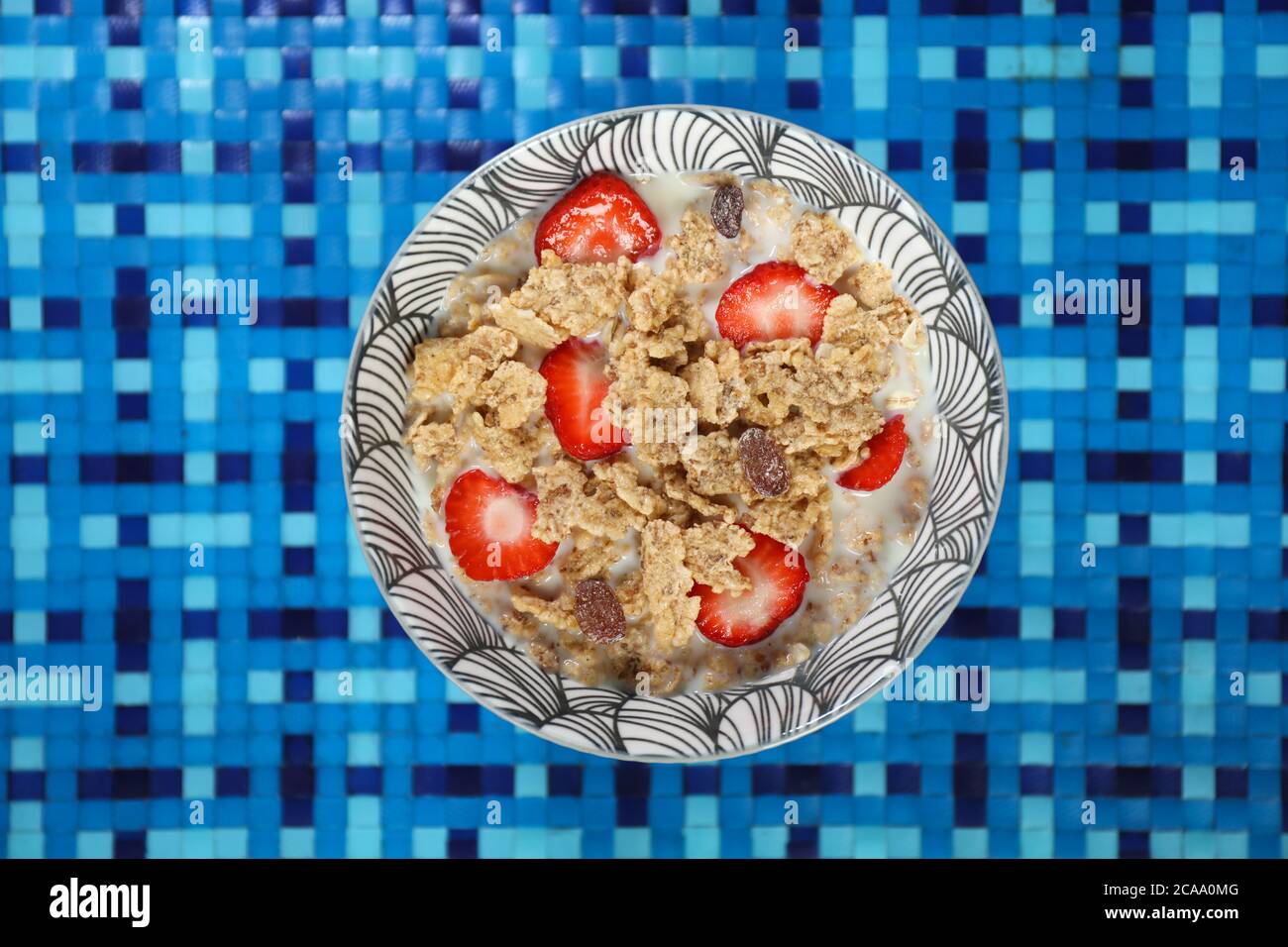 Gros plan de flocons de maïs et de lait avec fraise dans un bol vu d'en haut, isolé sur fond blanc bleu Banque D'Images