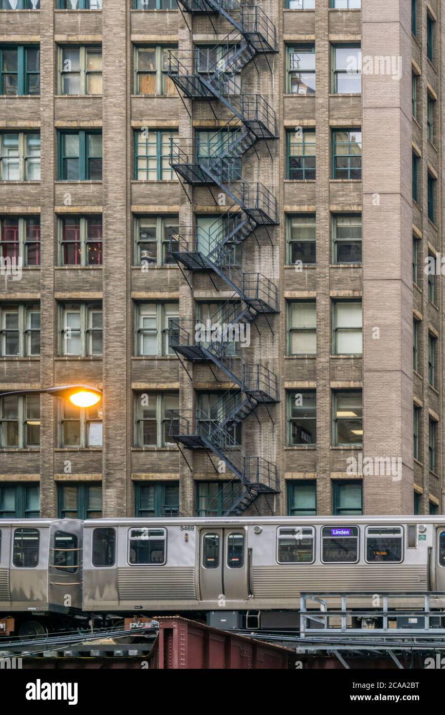 Le train El de Chicago passe devant un grand bâtiment commercial avec évacuation extérieure du feu de métal. Banque D'Images