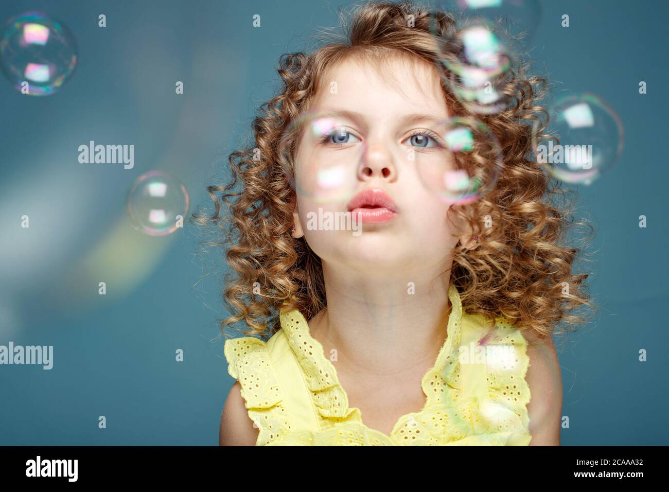 Enfant avec des bulles de savon. Petite fille soufflant des bulles de savon dans le studio. Banque D'Images