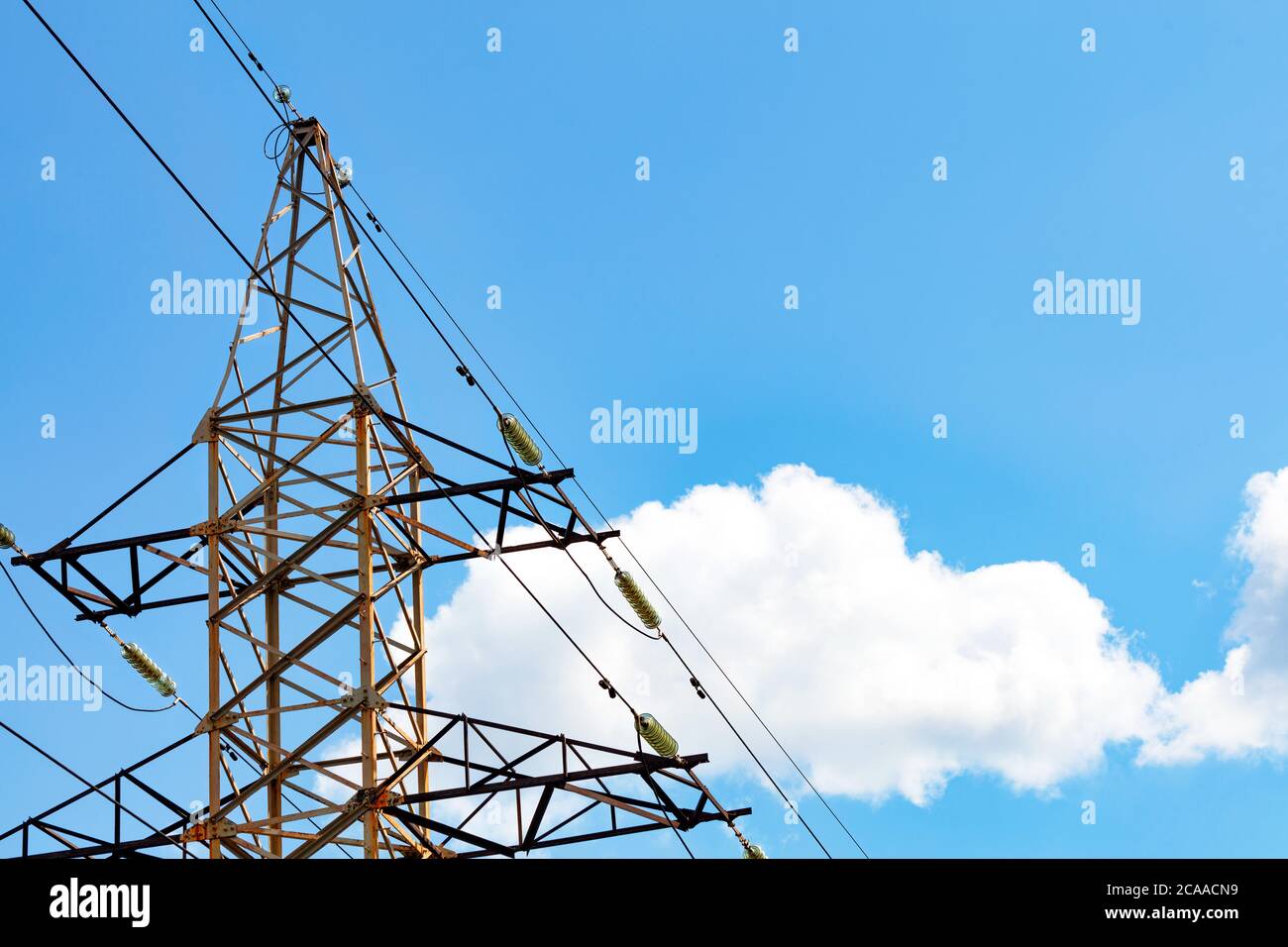 Un support de ligne électrique métallique avec des isolants et des fils utilisés pour supporter une ligne électrique aérienne contre un fond de nuage blanc et de ciel bleu, espace de copie. Banque D'Images