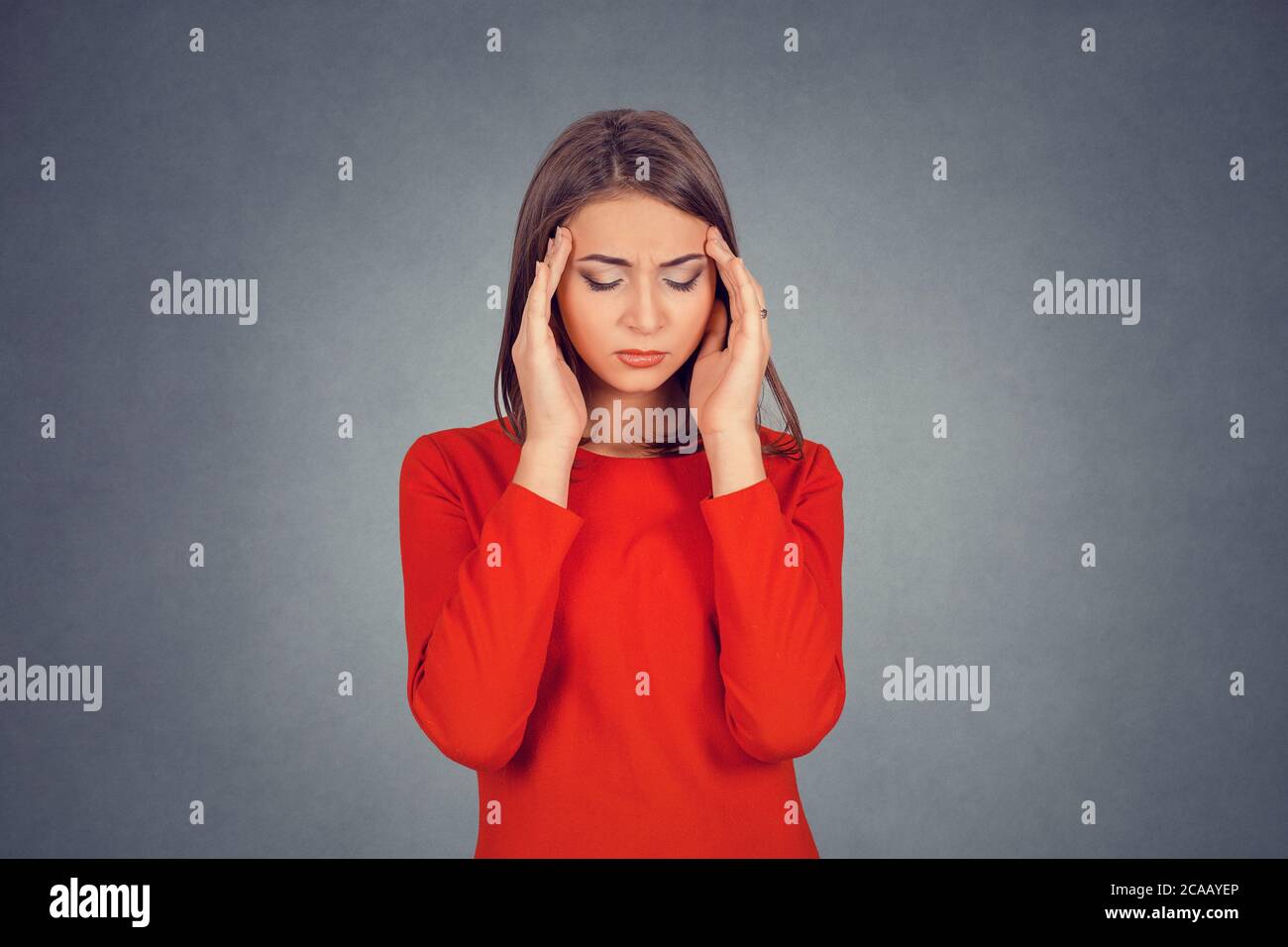 Portrait a souligné la jeune femme avec l'expression du visage inquiet mains sur sa tête regardant vers le bas. Femme d'affaires en robe rouge, Bob hairstyle. Isolé sur Banque D'Images