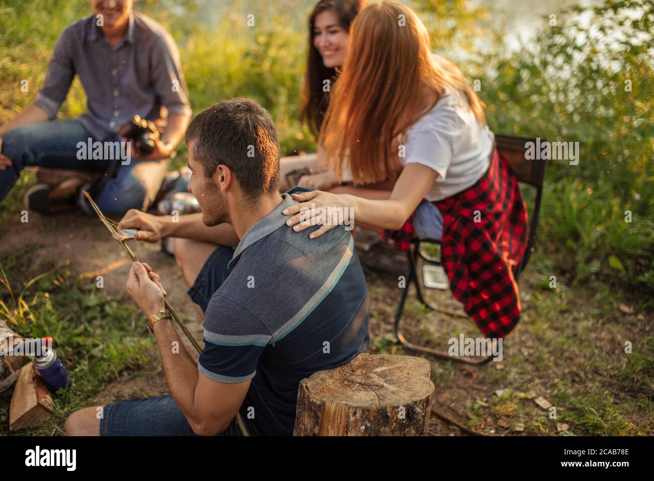 un type attrayant coupe un brunch d'arbre pour la pêche. le randonneur utilise un couteau pour préparer la nourriture. photo vue latérale Banque D'Images