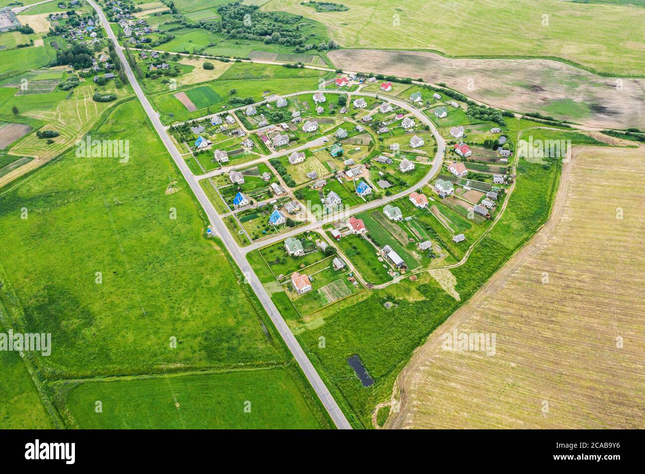 paysage rural aérien de petit village avec des maisons résidentielles parmi les champs verts cultivés Banque D'Images