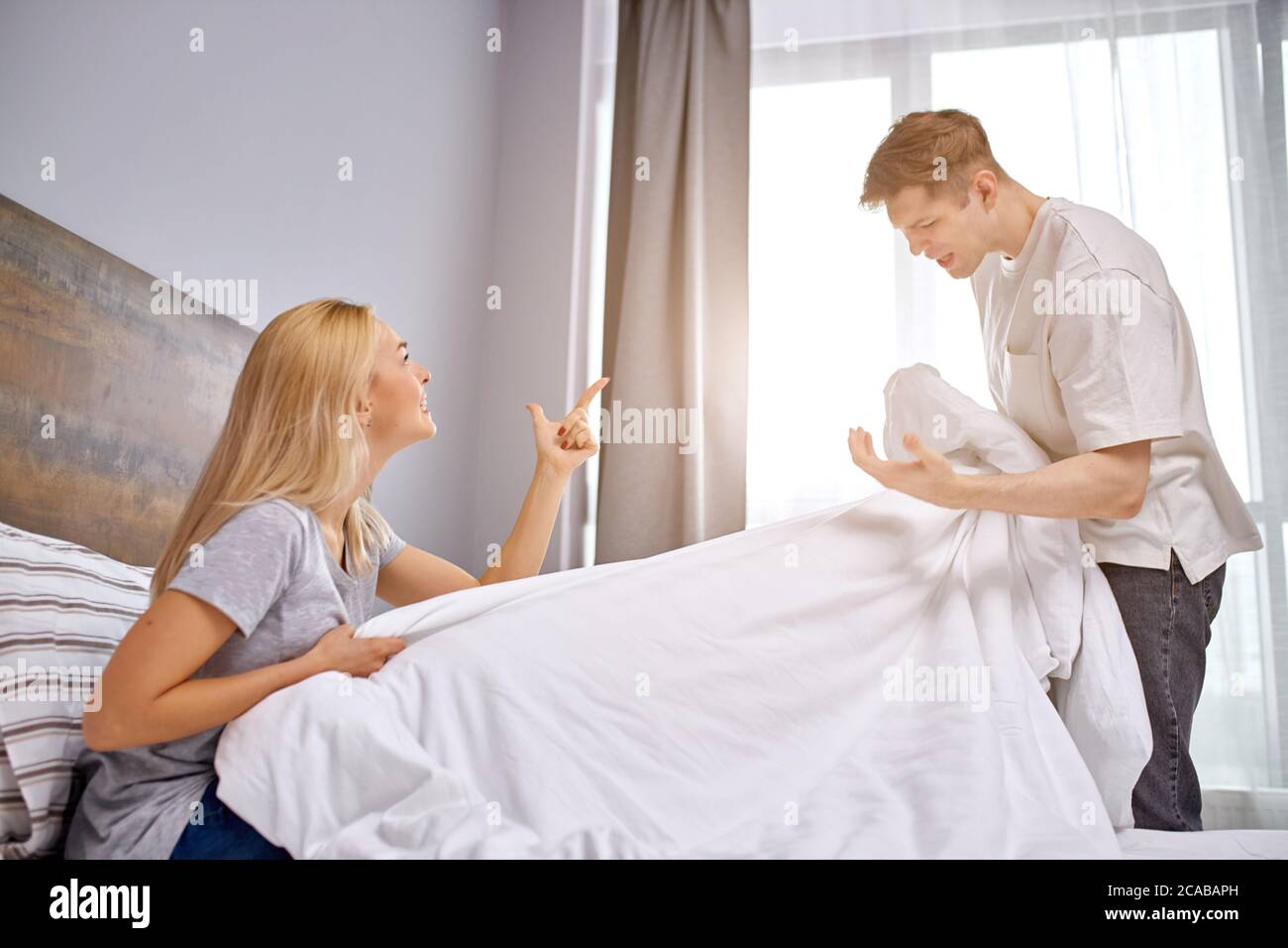 insatisfait de la vie de famille, mari et femme querelle dans le lit, l'homme tient une couverture entre les mains, crie à la femme, désaccord Banque D'Images