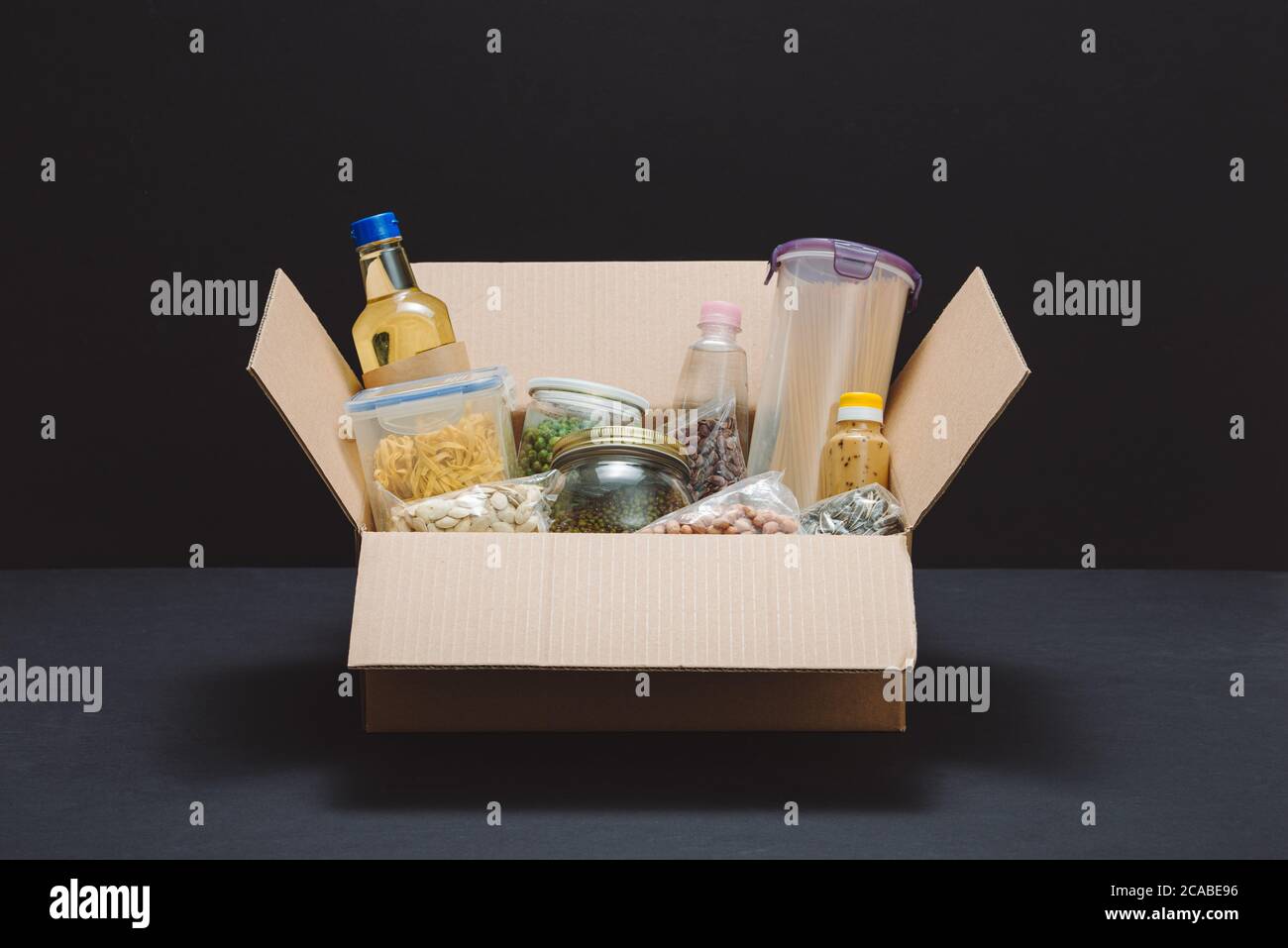 Donation box avec divers aliments. Ouvrir boîte en carton avec de l'huile, de la nourriture en conserve, céréales et pâtes alimentaires. Banque D'Images