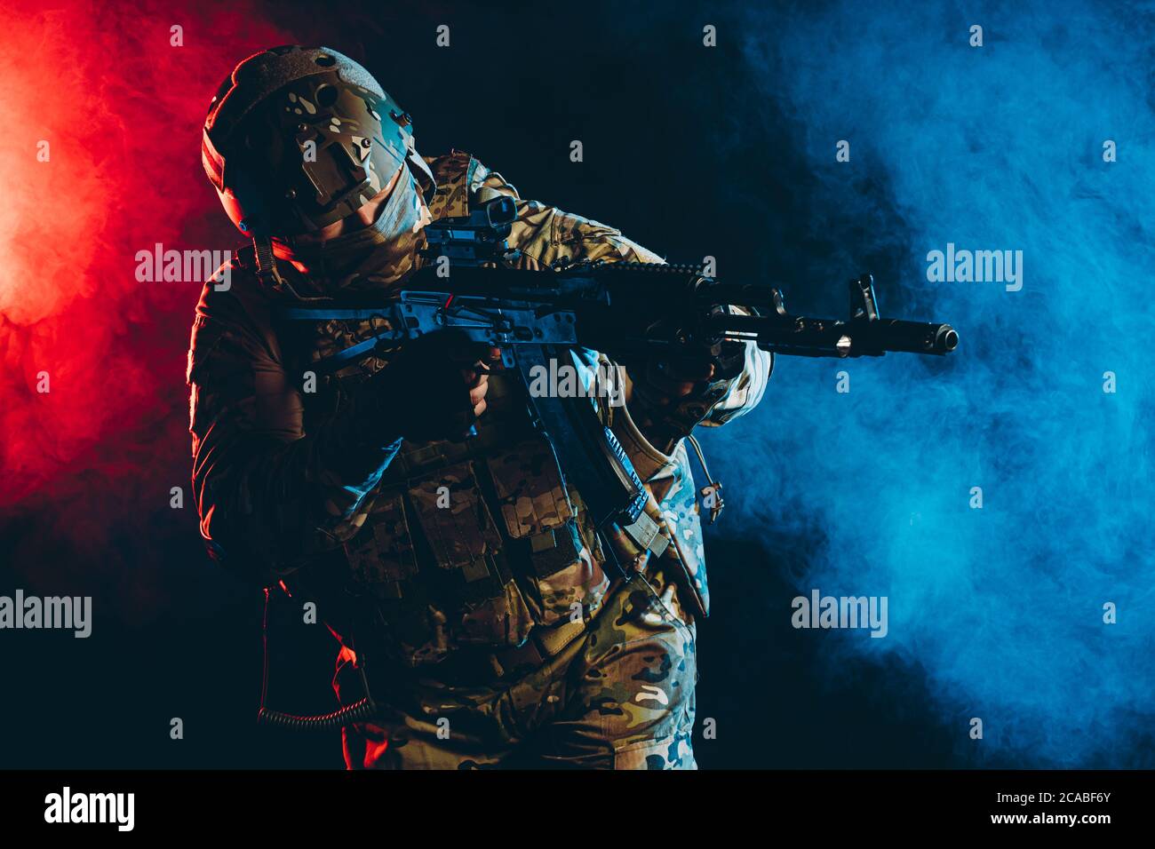 Soldat militant en action, portant un uniforme vert avec un équipement spécial, en tirant, pointant du côté du pistolet isolé sur fond UV fumé Banque D'Images