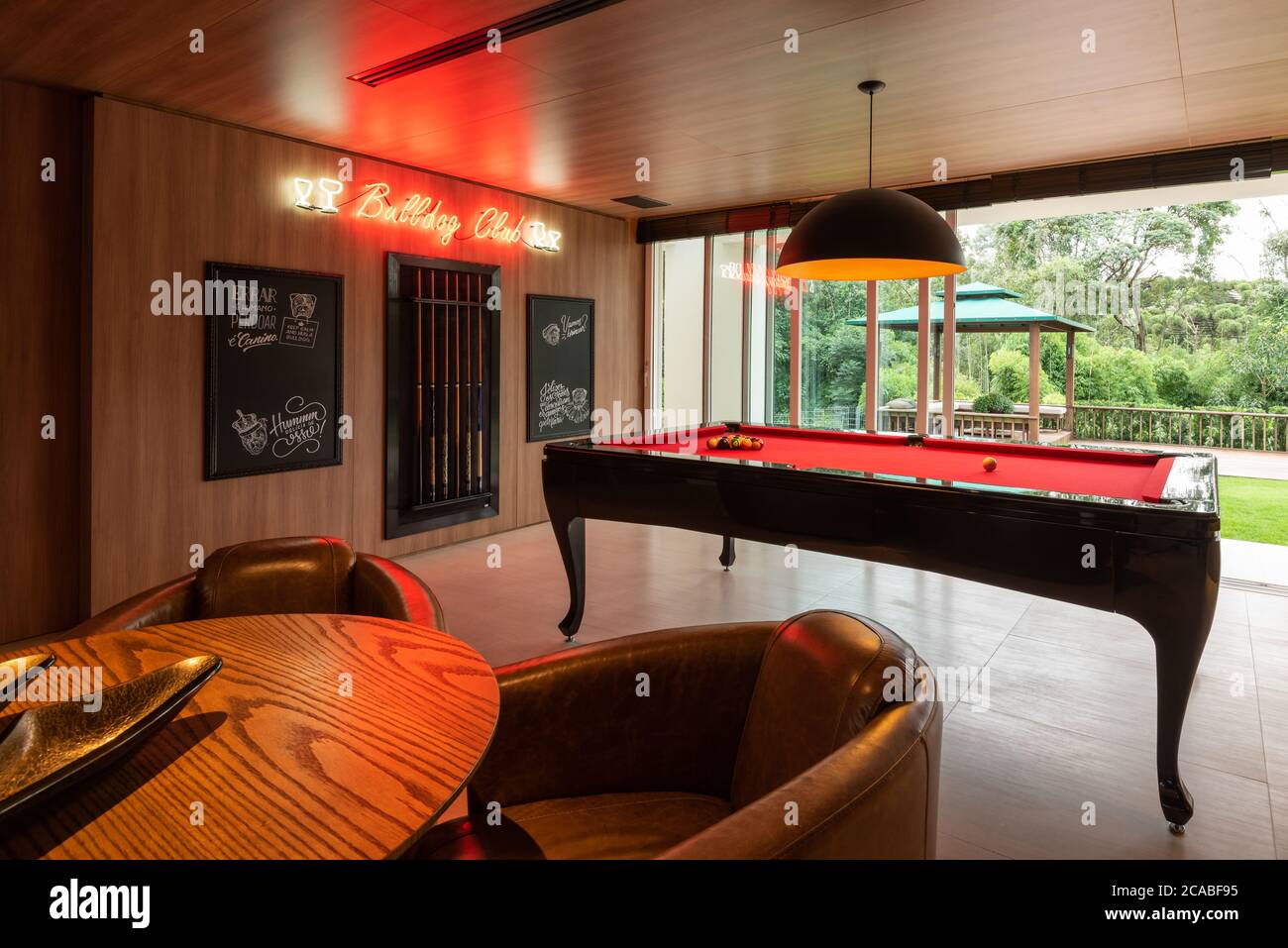 Table de billard rouge sur une salle de jeux avec de grandes fenêtres vue  sur la nature, panneaux de signalisation au néon pour chiens de taureau  Photo Stock - Alamy