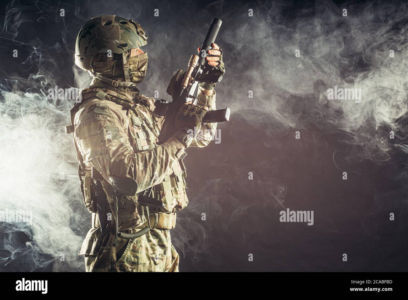 jeune militaire, soldat tenant un fusil portant des vêtements militaires, camouflage vert et casque sur la tête, combattant Banque D'Images