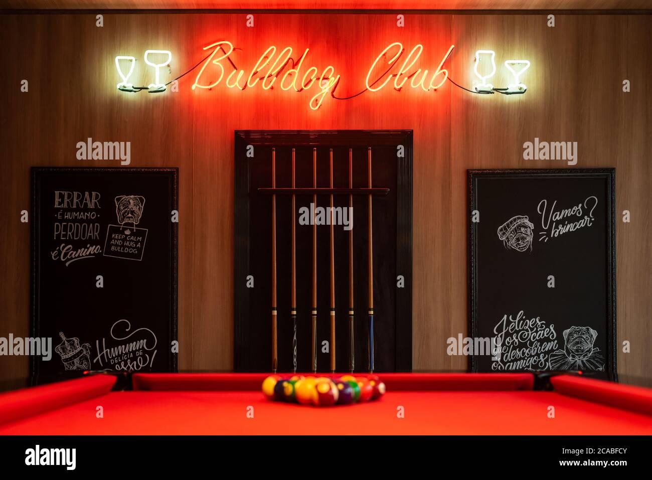 Table de billard rouge sur une salle de jeux avec de grandes fenêtres vue  sur la nature, panneaux de signalisation au néon pour chiens de taureau  Photo Stock - Alamy