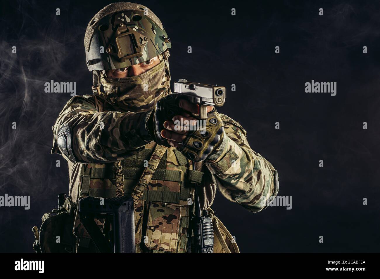 jeune militaire, soldat tenant un fusil portant des vêtements militaires, camouflage vert et casque sur la tête, combattant Banque D'Images