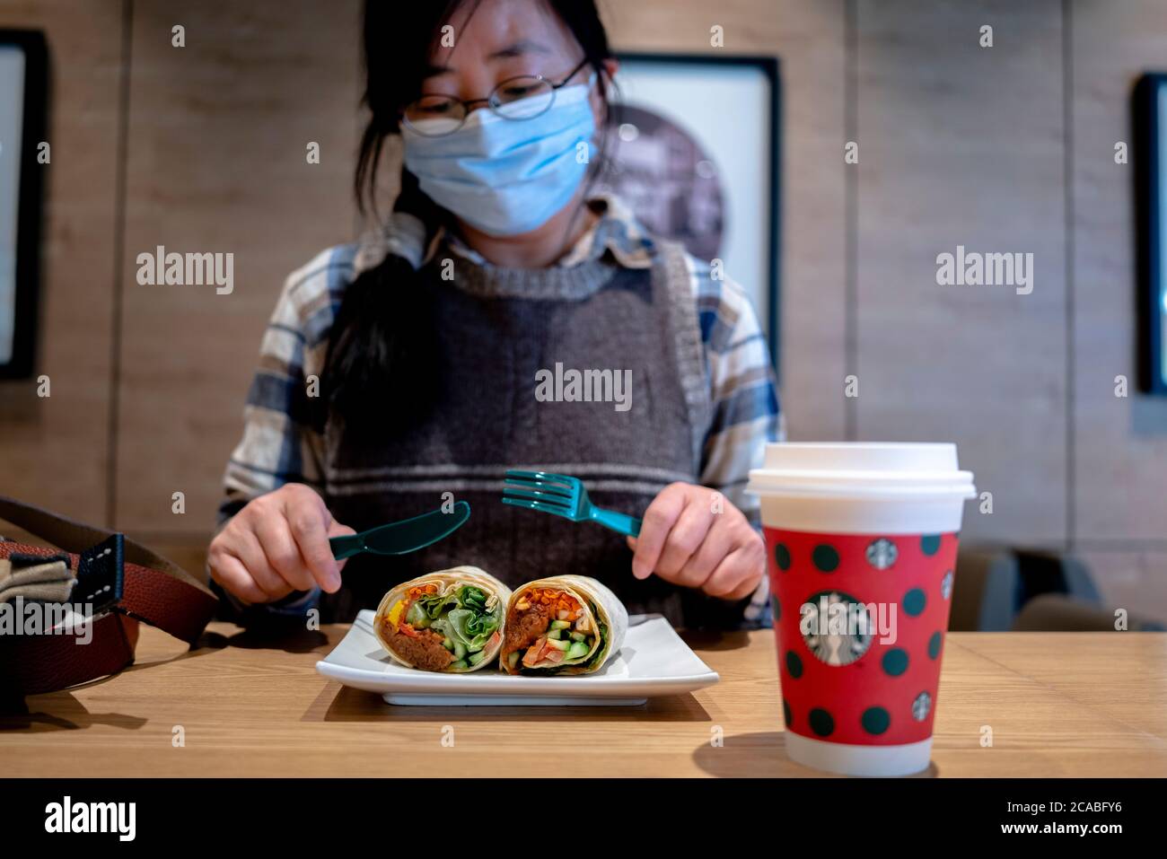 Une fille est prête à manger au-delà des rouleaux de viande, farcie avec du bœuf et des légumes alternatifs dans un café Starbucks. Banque D'Images Une fille est prête à manger au-delà des rouleaux de viande, farcie avec du bœuf et des légumes alternatifs dans un café Starbucks. Banque D'Images