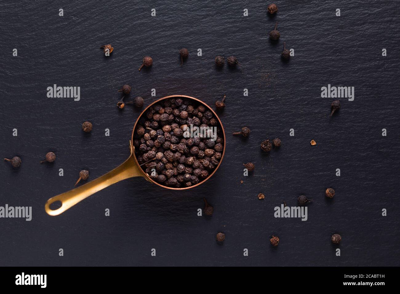 Food Spices concept vue de dessus du poivre noir biologique en cuivre sur pierre d'ardoise noire avec espace de copie Banque D'Images