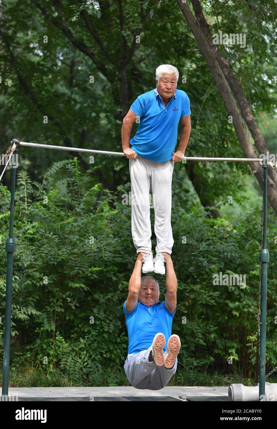 (200806) -- TIANJIN, le 6 août 2020 (Xinhua) -- Tong Yugen (en haut) de 66 ans et Shen Qi de 76 ans, font de l'exercice dans le parc Xigu, dans le nord de la Chine Tianjin, le 4 août 2020. Un groupe de personnes âgées a formé une équipe de gymnastique à Tianjin il y a dix ans. Ils ont pratiqué régulièrement comme exercice physique quotidien. L'équipe compte maintenant plus de 20 membres, avec une moyenne d'âge de 68 ans. « l'exercice nous permet de maintenir un bon état physique, ce qui est très utile pour améliorer la qualité de vie. » a déclaré Tong Yugen, le chef d'équipe âgé de 66 ans. À mesure que l'équipe devient plus connue, plus de 100 amateurs de fitness ont rejoint t Banque D'Images