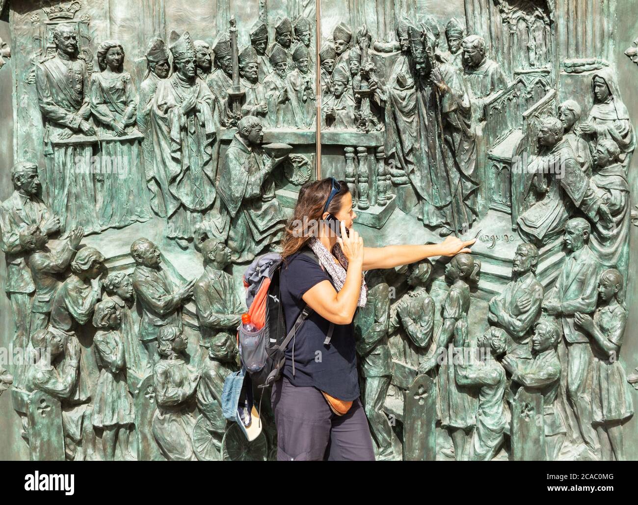 Une touriste féminine utilisant un téléphone portable à l'extérieur de la cathédrale de Madrid.le roi Juan Carlos et la reine Sofia à la porte (en haut à gauche) de la cathédrale d'Almudena à Madrid, en Espagne. Banque D'Images