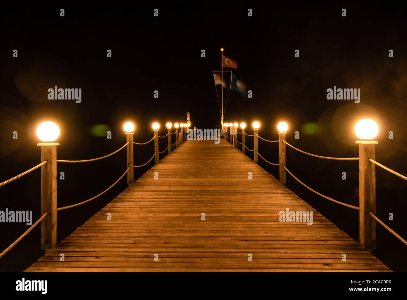 Jetée en bois illuminée la nuit, lumières sur un pont en bois au bord de la mer en Turquie. Promenade en bord de mer avec lanternes, lampes rondes. Vacances touristiques d'été Banque D'Images