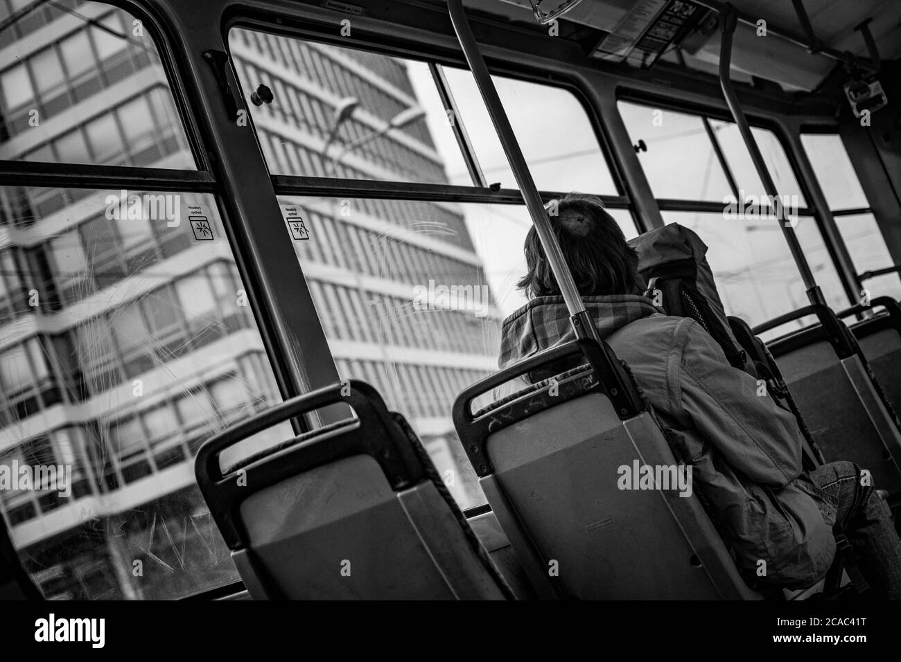 un homme sans domicile se déplace dans un vieux tramway et regarde l'architecture par une fenêtre rayée Banque D'Images