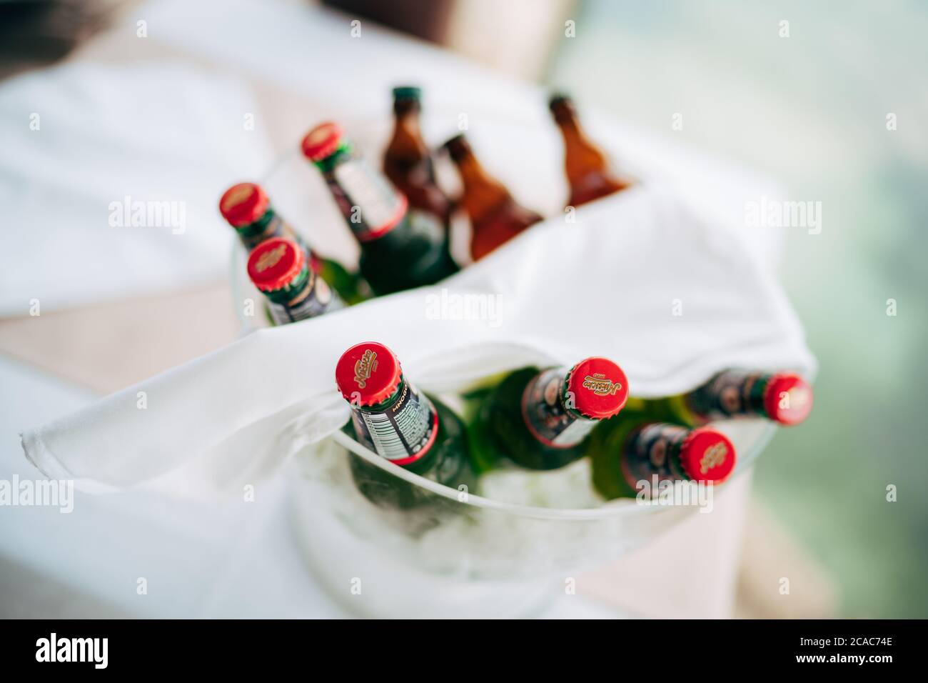 Un seau à glace transparent avec des bouteilles pleines de bière claire et foncée et une serviette blanche sur le dessus. Banque D'Images