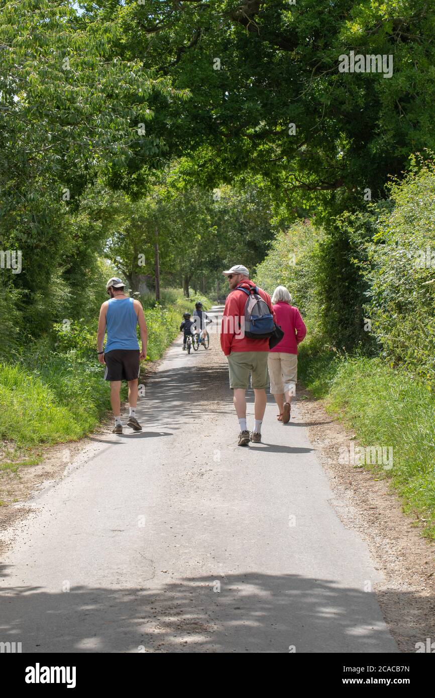 Adultes, grand-mère, père et oncle, regardant plus de deux petits-fils sur leurs vélos en longeant une route de campagne tranquille et sûre. Norfolk. ANGLIA est. ROYAUME-UNI. Banque D'Images