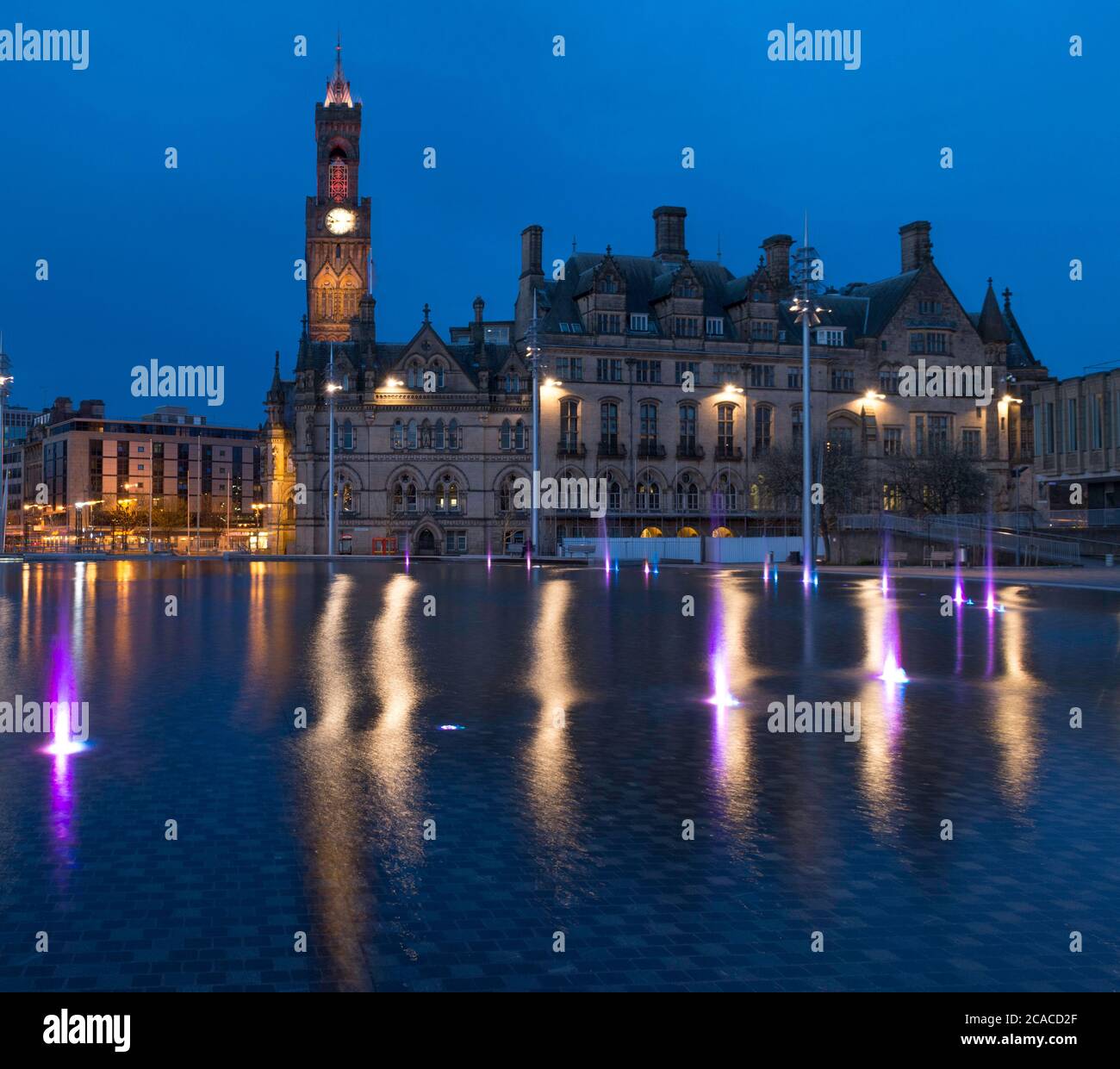 Vue en soirée sur l'hôtel de ville, la piscine miroir et les fontaines du parc Bradford City Park Banque D'Images