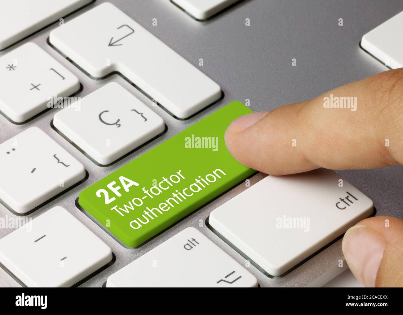 Authentification à deux facteurs 2FA écrite sur la touche verte du clavier métallique. Touche enfoncée avec le doigt Banque D'Images