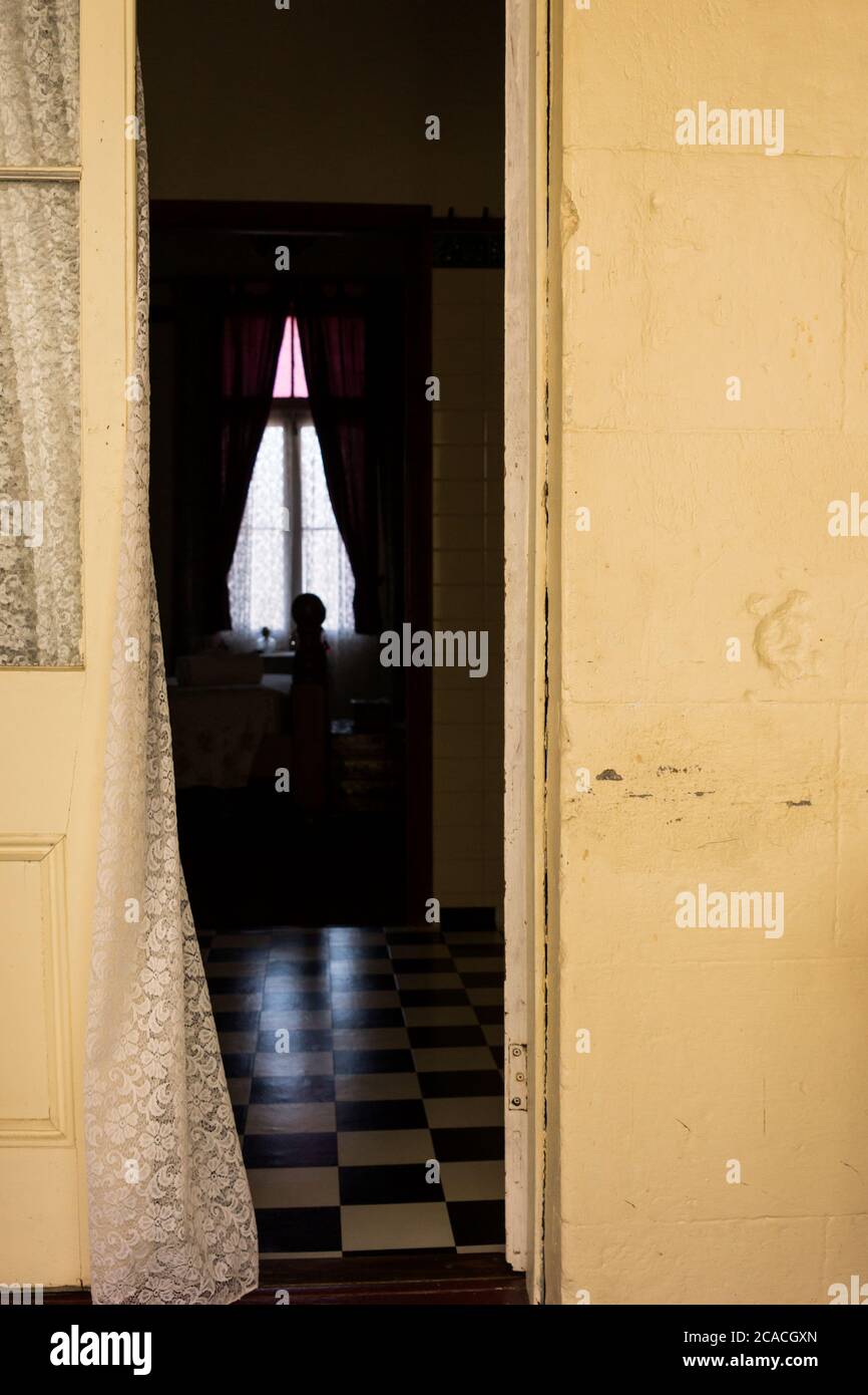 Rideau soufflant dans une porte ouverte à une chambre dans une maison de style Queenslander ancienne avec portes-fenêtres Banque D'Images