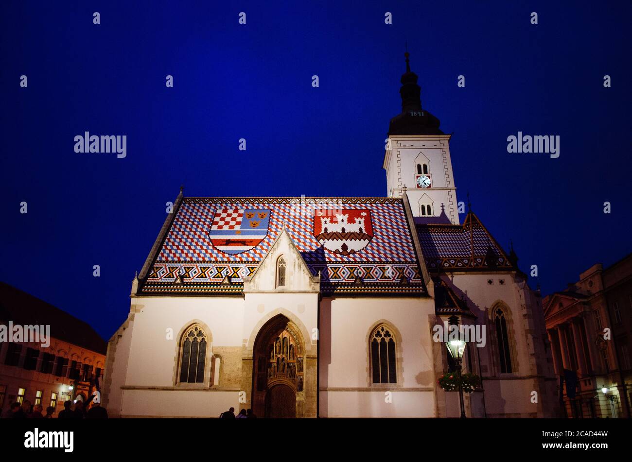 L'église Saint-Marc de Zagreb, Croatie, illuminée et en contraste avec le bleu foncé et la soirée nuageux en arrière-plan. Banque D'Images