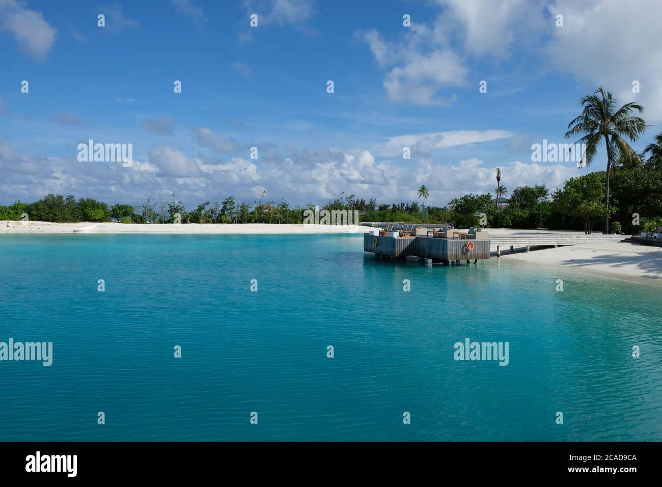 Terrasse extérieure dans le complexe de l'île de Maldive. Bleu vert eau de mer. Large ciel bleu ensoleillé nuage blanc et palmiers Banque D'Images