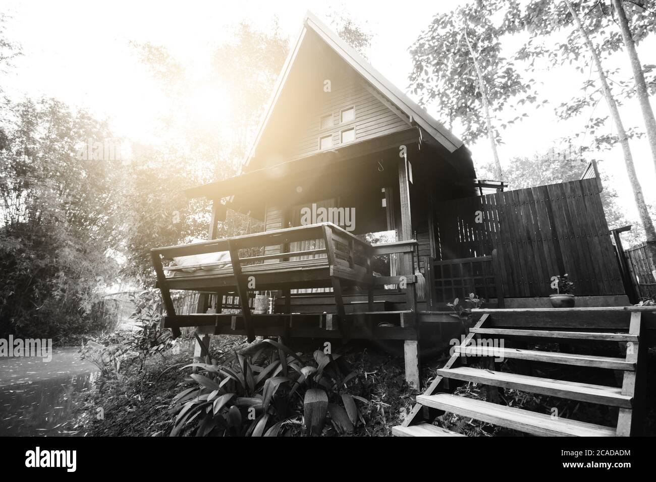 Maison thaïlandaise en bois dur sur le côté de la rivière en noir et blanc avec lumière du soleil et lumière de la lumière du soleil. Le style unique de toit haut est adapté aux tropiques Banque D'Images