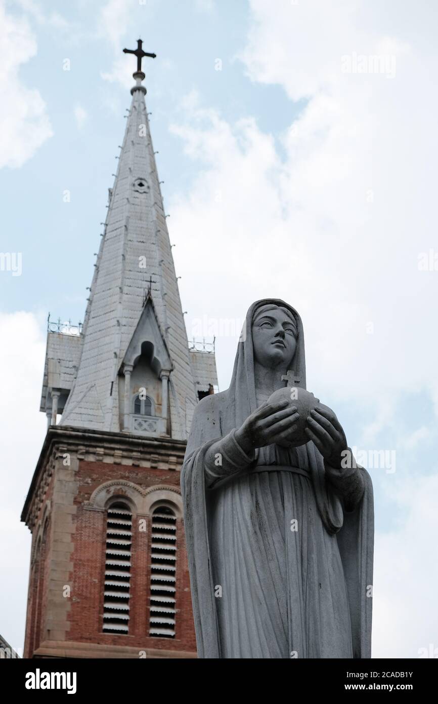 Gros plan de la statue de la Sainte Vierge Marie devant l'église rouge à Ho Chi Minh-ville Vietnam. Banque D'Images