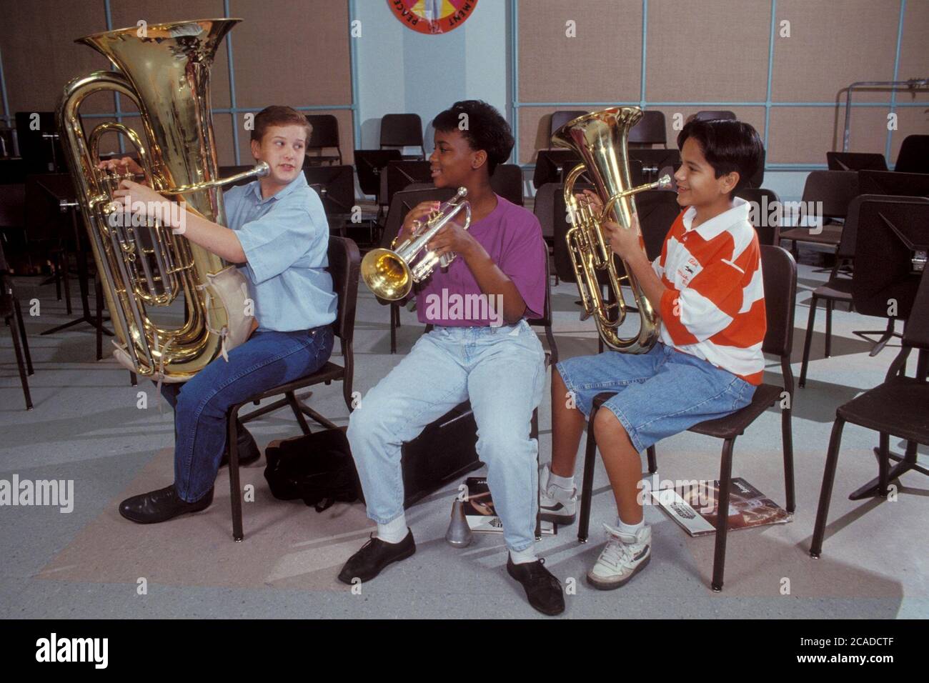 Le garçon anglo joue du tuba, tandis que la fille afro-américaine joue de la trompette et le garçon hispanique joue de l'euphonium pendant la répétition de bande de collège. ©Bob Daemmrich Banque D'Images
